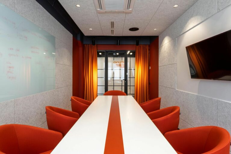 Elegant and colorful conference room with orange chairs and modern decor.