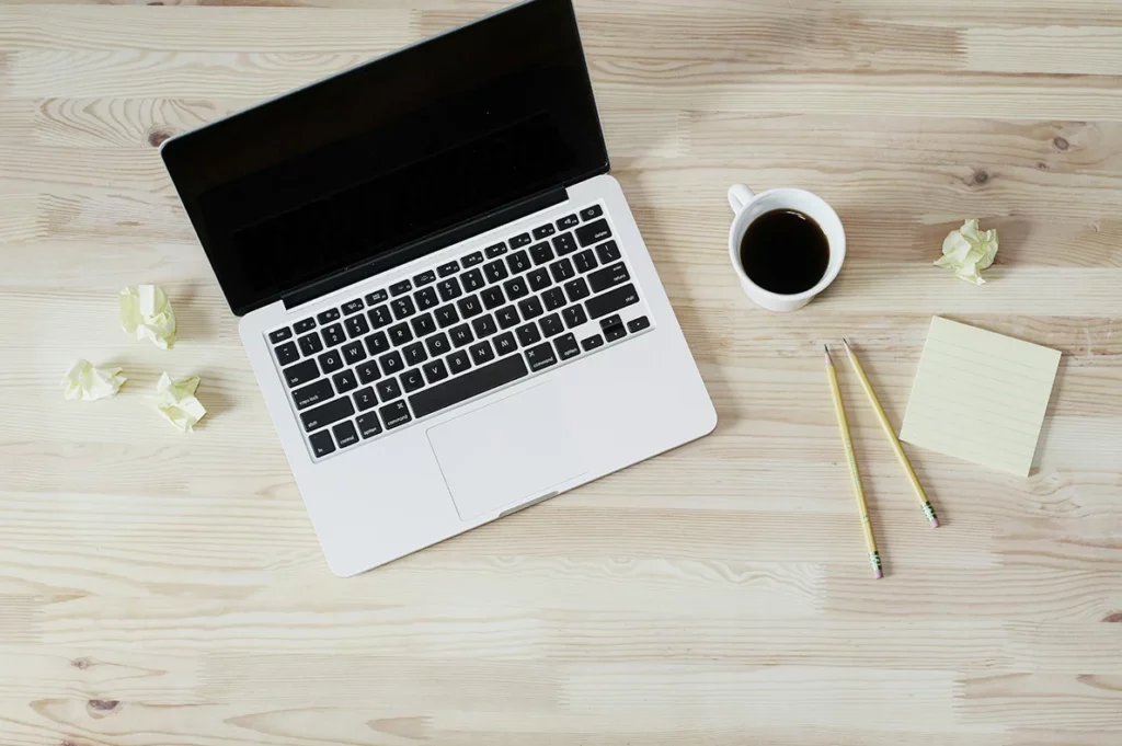 A laptop, pen, and notes on a desk, symbolizing productivity and organization for professional tasks.