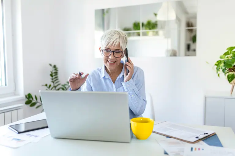 Older woman on the phone while sitting in front of a laptop