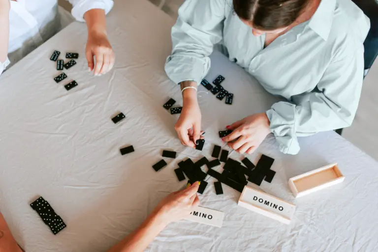 Women playing a game of domino on a white sheet