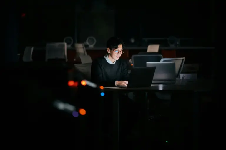 Man sitting in the dark working on a laptop