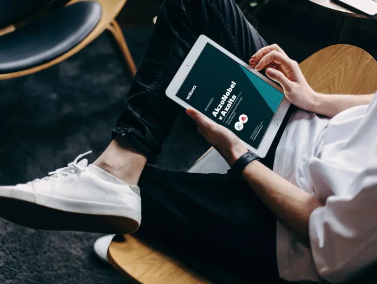 Professional reviewing Valona Intelligence M&A flash analysis report on tablet showing AkzoNobel and Axalta merger competitive intelligence insights for chemical industry market analysis