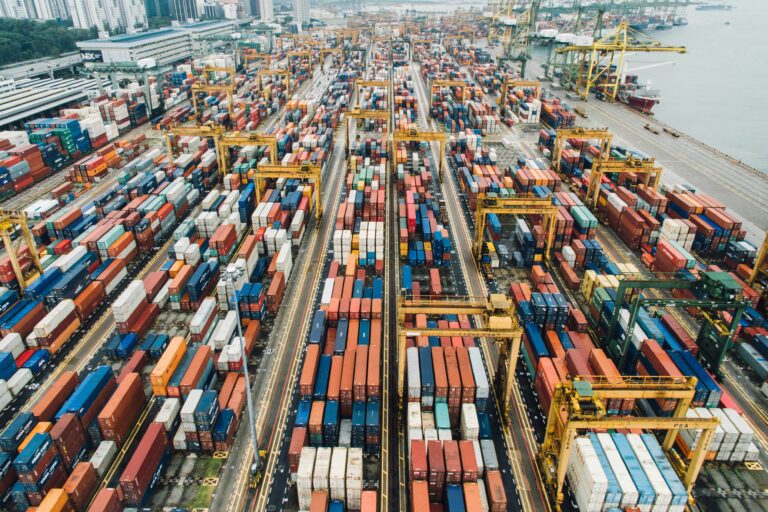 Shipping containers in a busy port Photo by CHUTTERSNAP on Unsplash